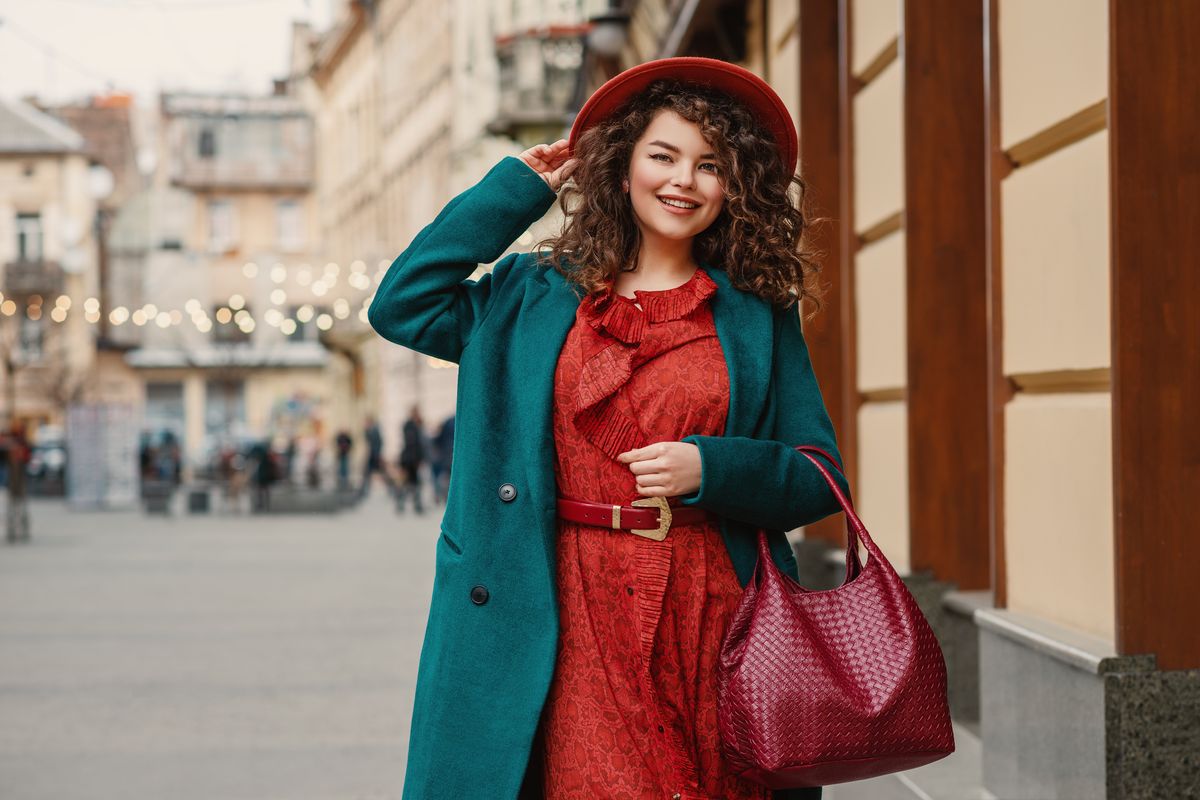 Moda curvy, ragazza con abito rosso e cappotto verde