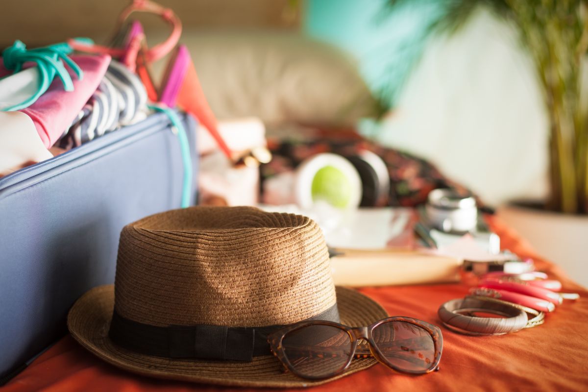 Valigia, cappello di paglia e occhiali da sole