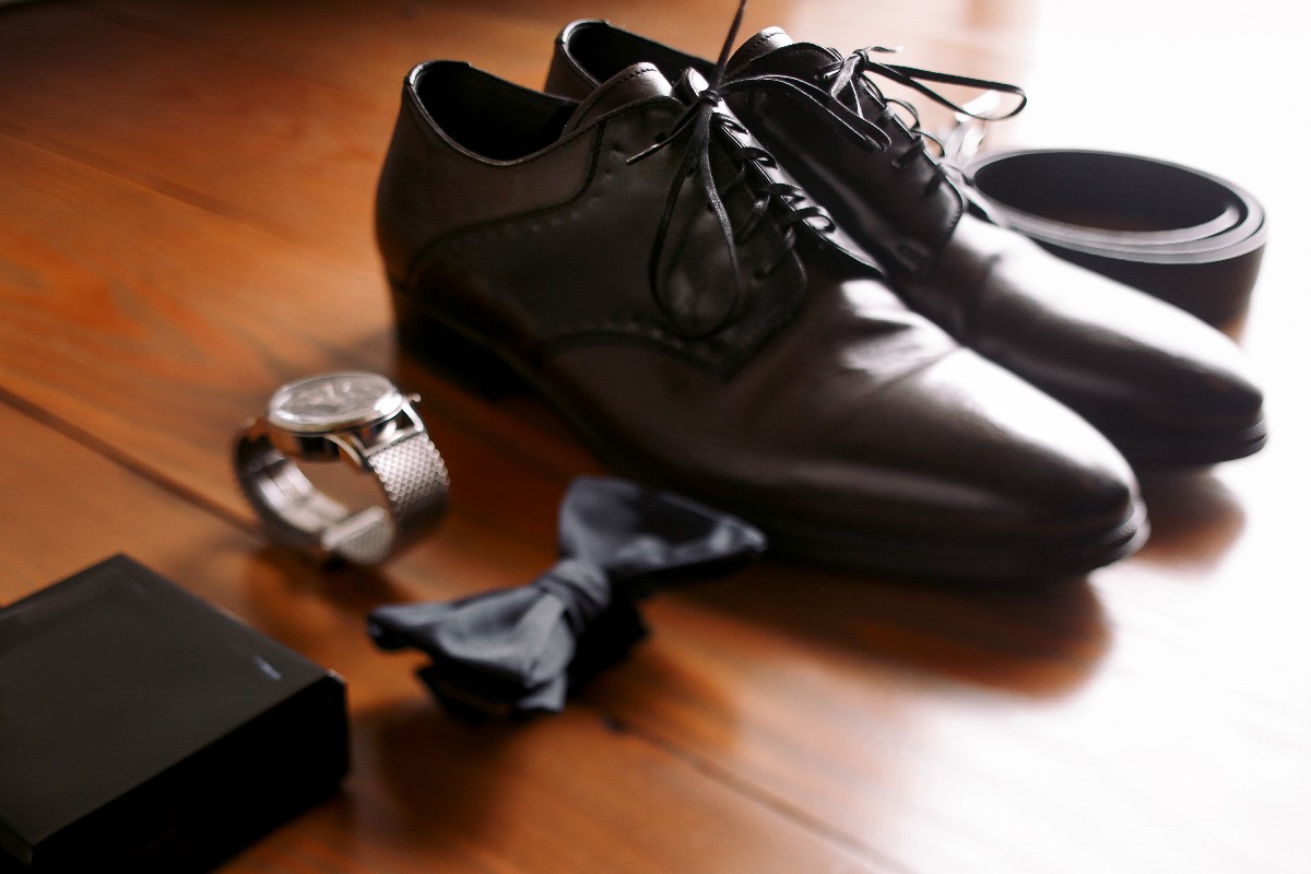 Dettagli di stile maschile: scarpe eleganti, orologio, papillon e cintura.
