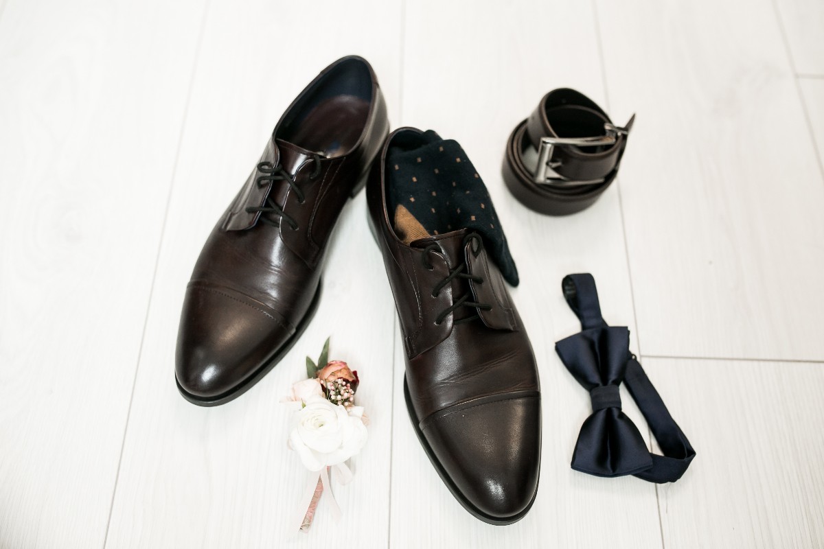 Accessori da sposo: un papillon, una cintura, una bottoniera e scarpe da uomo.