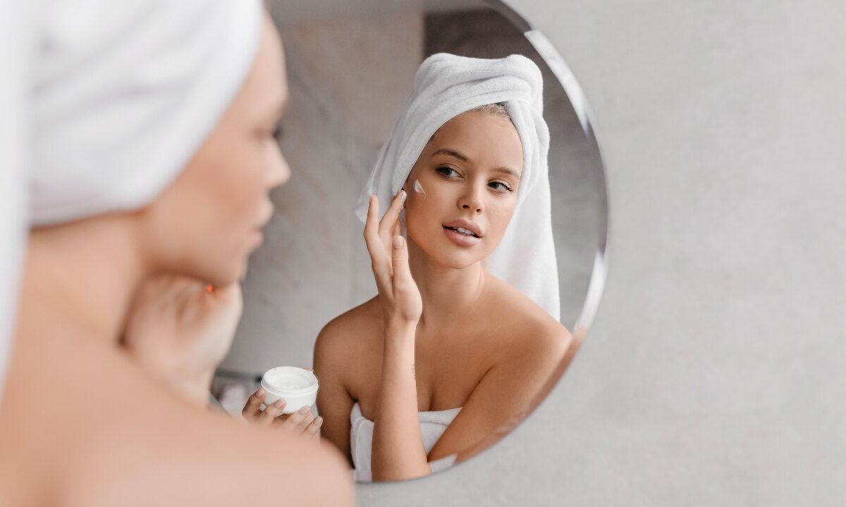 Giovane donna applica crema viso