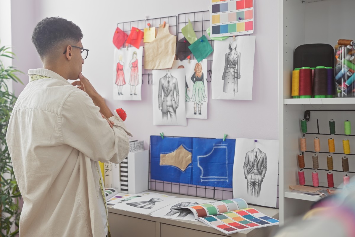 Fashion designer in sartoria che osserva modelli e campioni di tessuti.