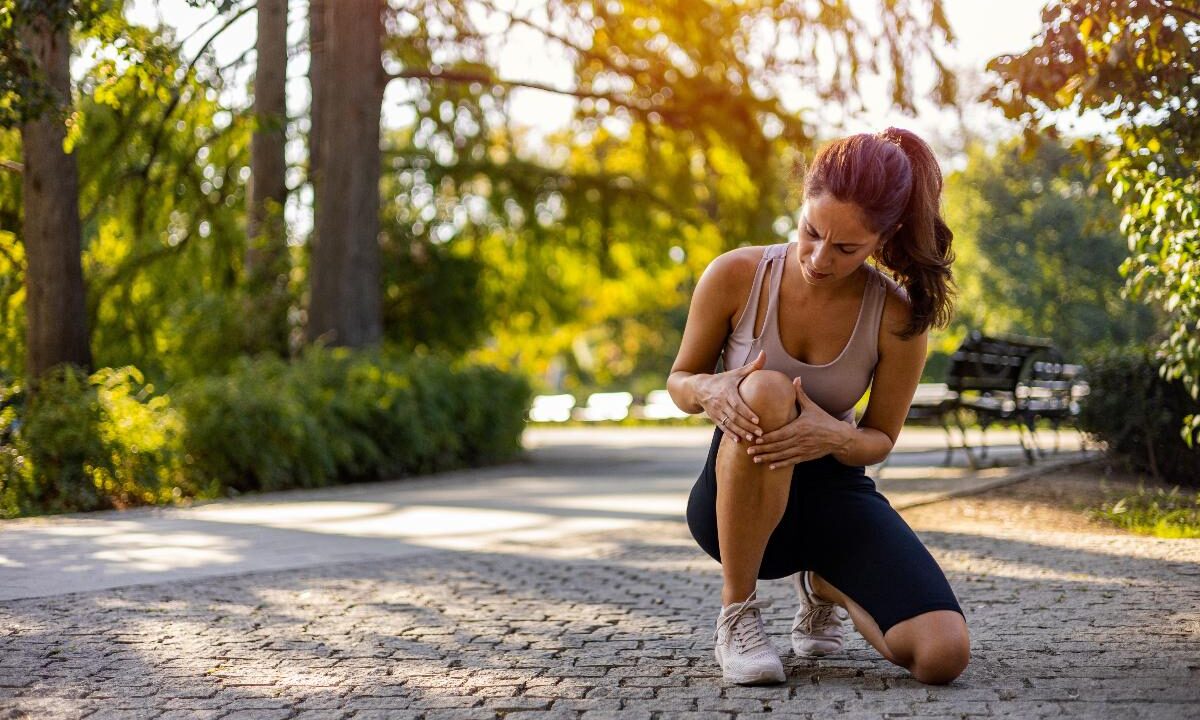 Donna che si ferma durante la corsa a causa di dolore al ginocchio.