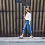 Outfit semplice in città: ragazza cammina indossando jeans e camicia.