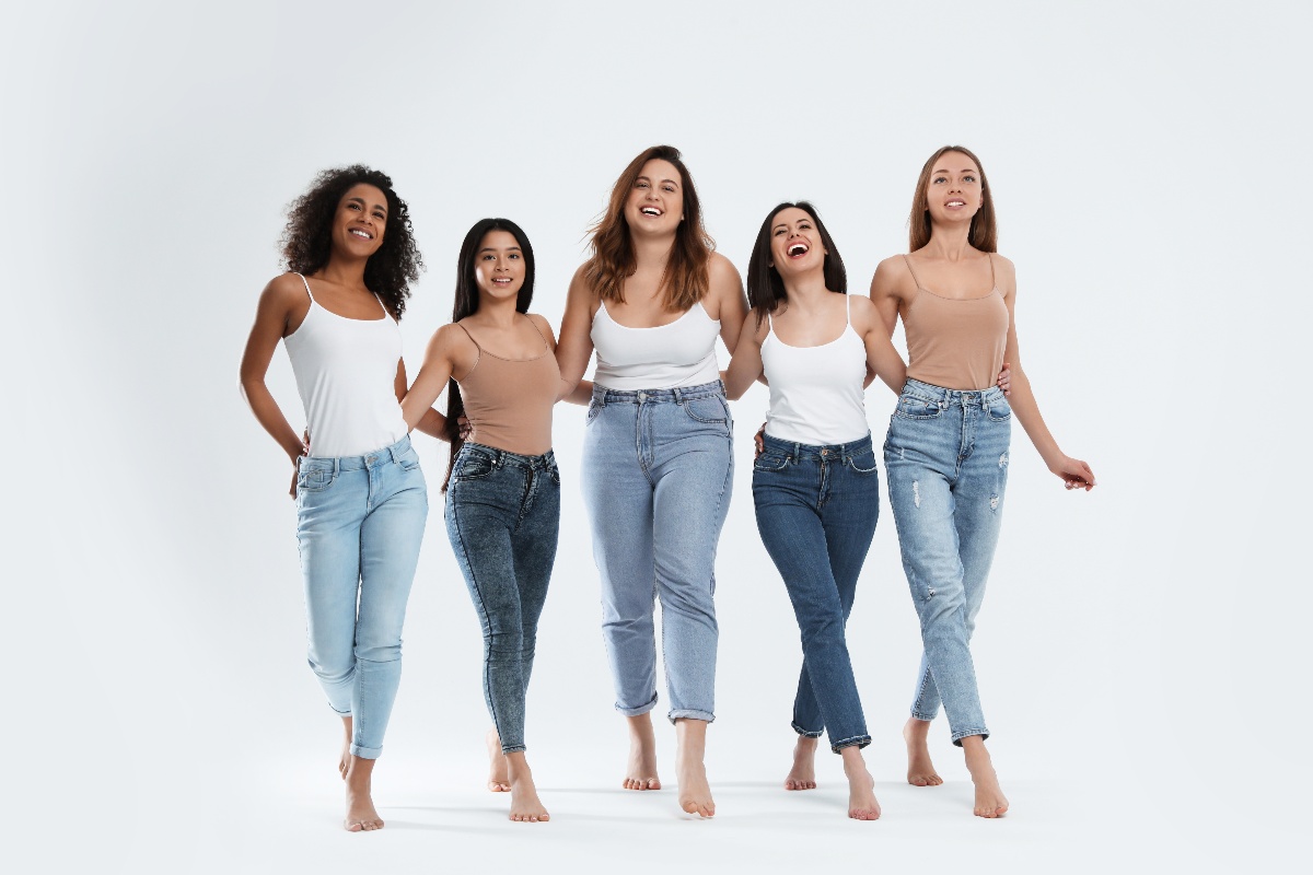 Ragazze e jeans colorati: diverse fisicità celebrano la varietà cromatica.