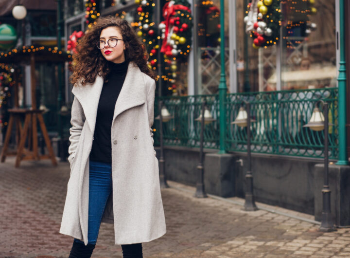Look invernale: ragazza in cappotto grigio davanti a un locale addobbato per Natale.