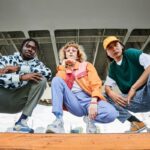 Stile streetwear: tre ragazzi con outfit colorati in stile urbano.