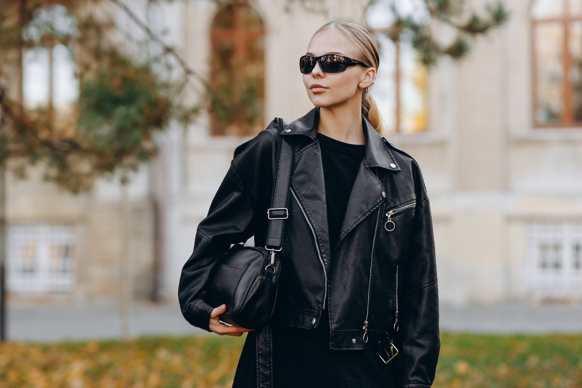 Ragazza con un look total black: giacca di pelle e occhiali da sole.